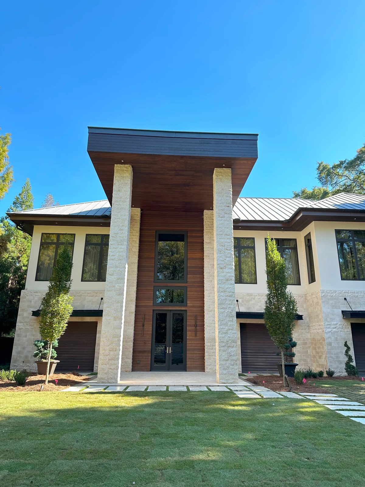 Monumental split-face limestone columns and cladding anchor a modern two-storey entrance.