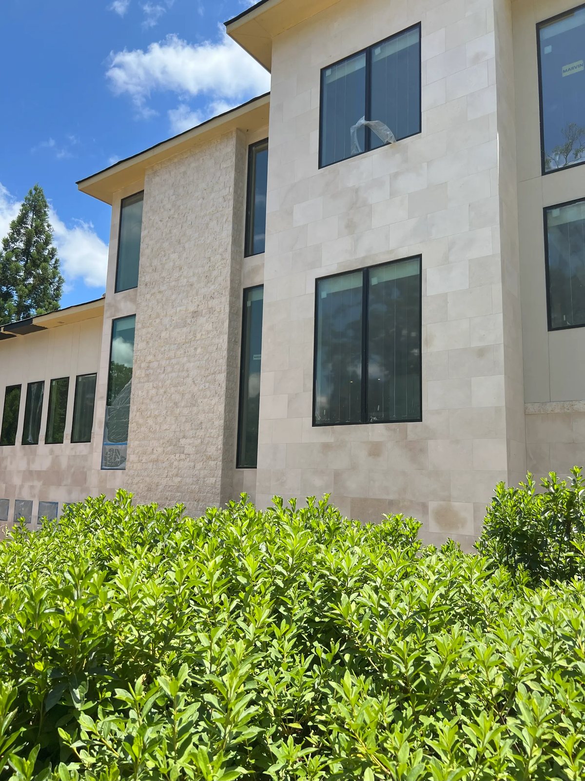 Sawn limestone panels paired with a split-face limestone feature column on a modern façade.